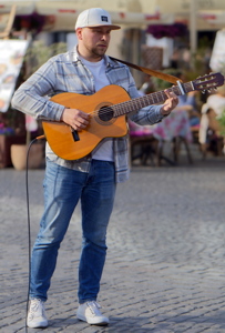 Talented street musician engrossed in playing his guitar on the cobblestone street